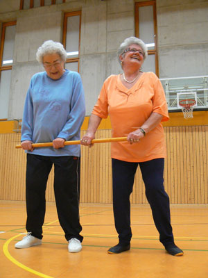 zwei ältere Damen betreiben Gymnastik in einer Turnhalle